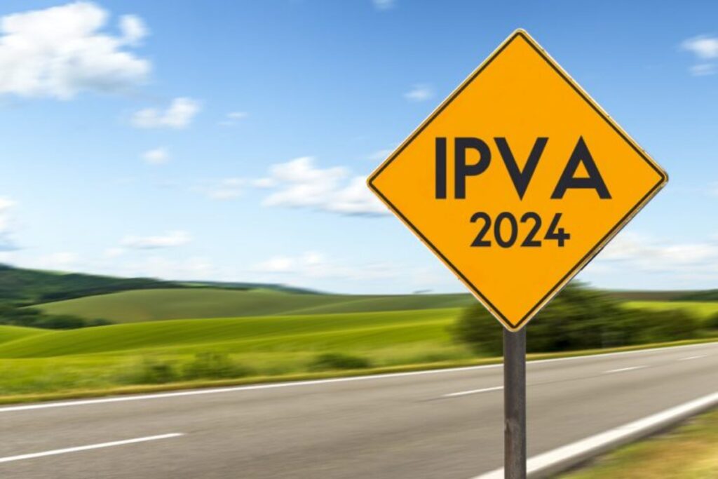 Placa amarela "IPVA 2024" com paisagem ao fundo.