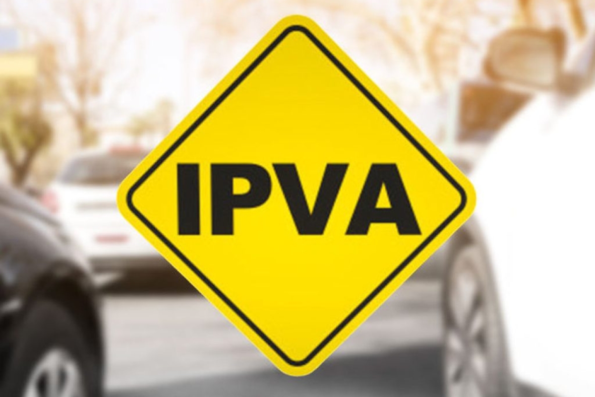 Placa amarela sinaliza IPVA com carro ao fundo.
