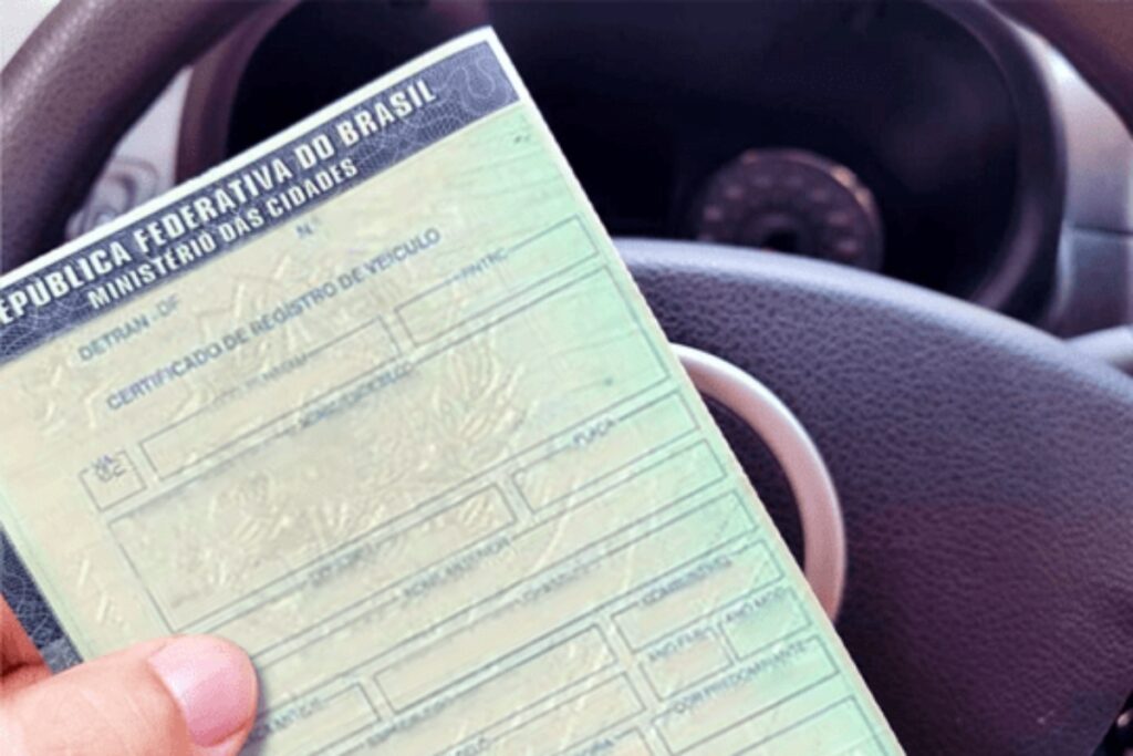Documento de veículo segurado por mão, interior de carro.