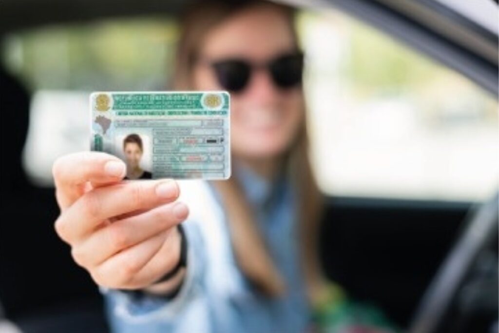 Mulher mostrando carteira de motorista no carro.